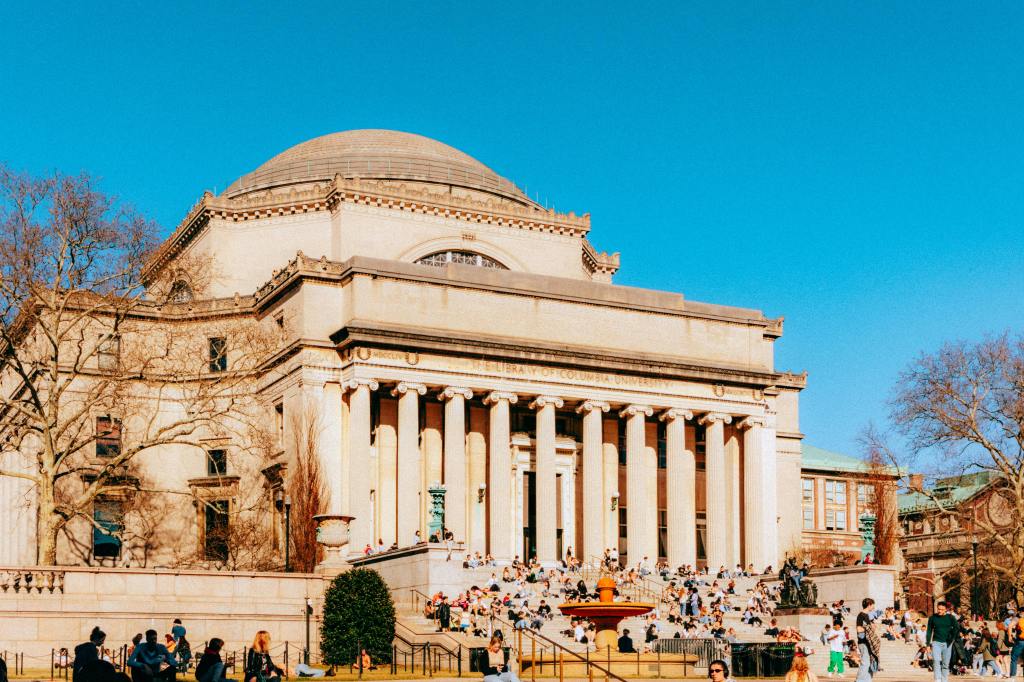Columbia University Library in new York in a sunny ay with many students on its stairs
